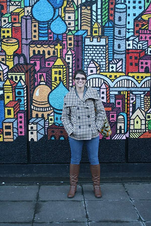 Ms. Hernandez in front of a mural wall