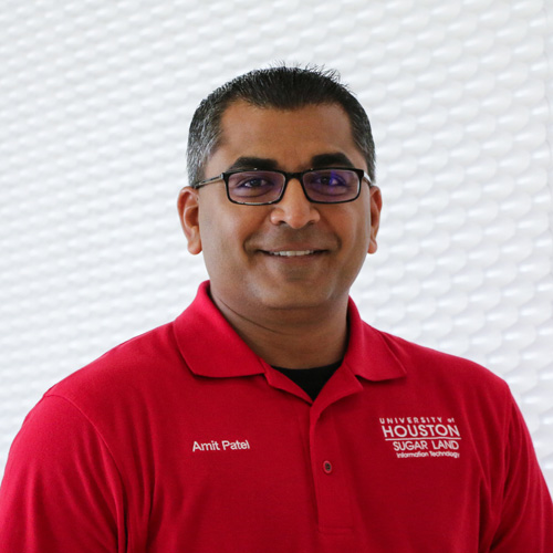 Portrait of an South Asian man smiling with glasses wearing a red polo shirt