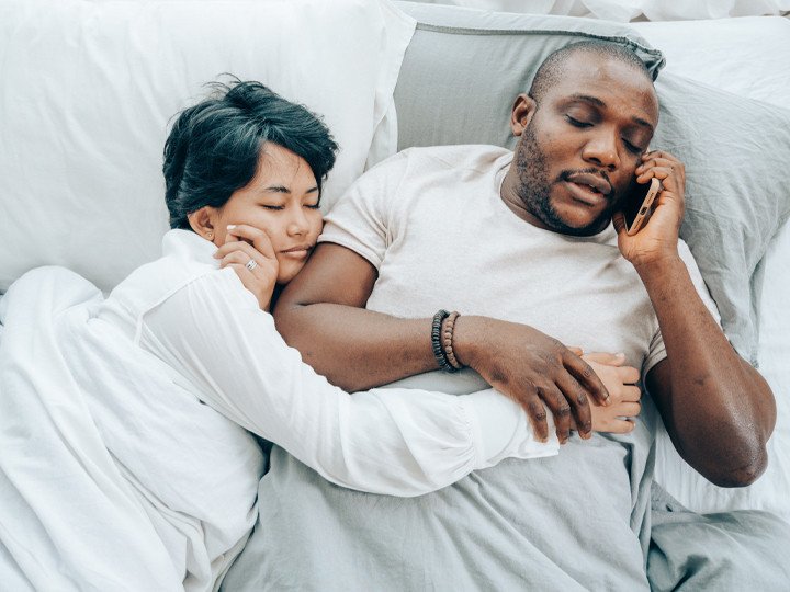 couple in bed man on phone