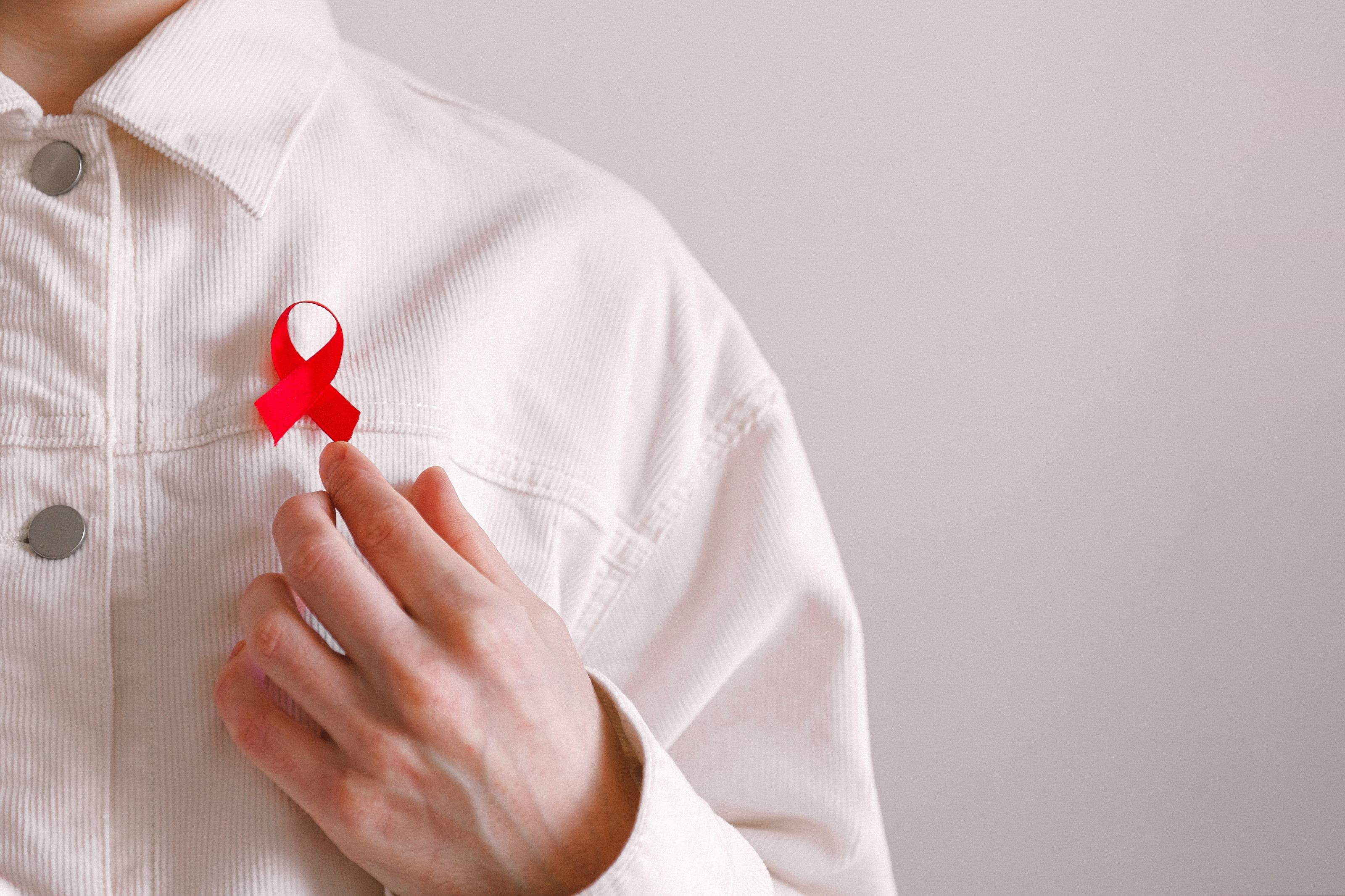 A photo of a person wearing a white shirt with a red ribbon pinned onto it.