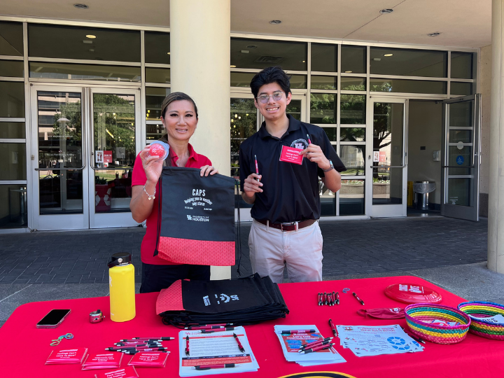 Two University of Houston community members holding up merchandise from the University counseling cetner