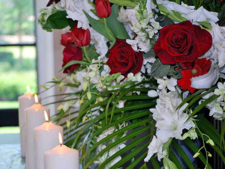 Picture of flower arrangement and lit up candles for memorial service.