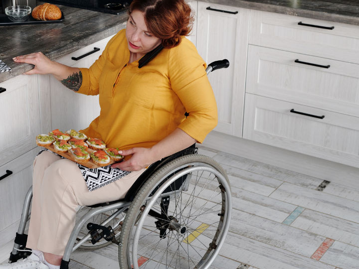 Woman in a wheelchair with food holding phone on her sholder
