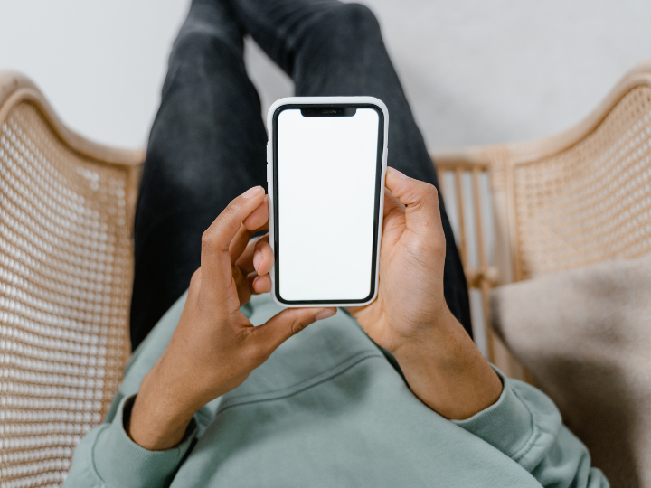 Person wearing jeans sitting on a couch with cell phone in hand