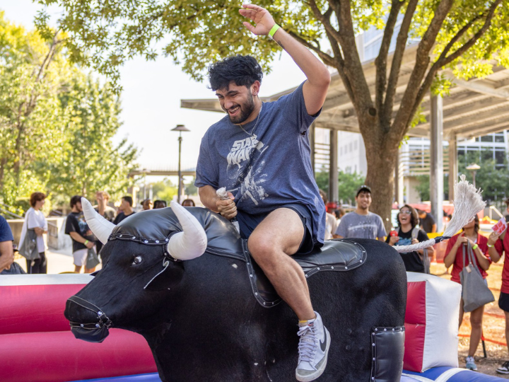 A student having fun riding a bull riding machine