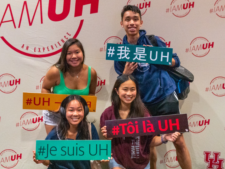 four UH students holding up IAMUH sign in different languages