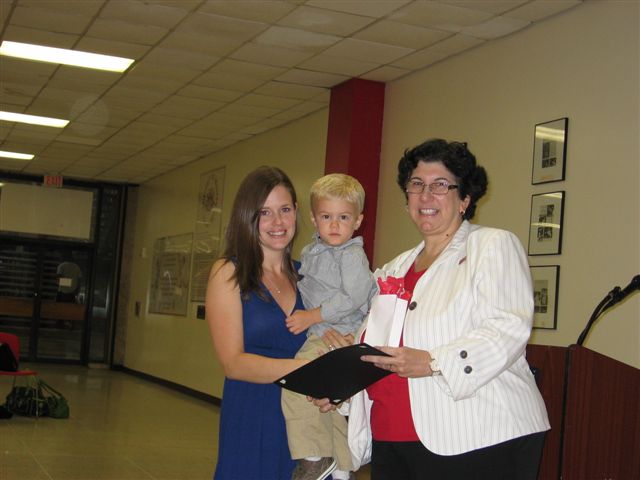 Carrie Foley being helped by one of her twin sons while receiving the Bobbie Snelling Bumblebee Award (for doing the impossible) from Dr. Maher.