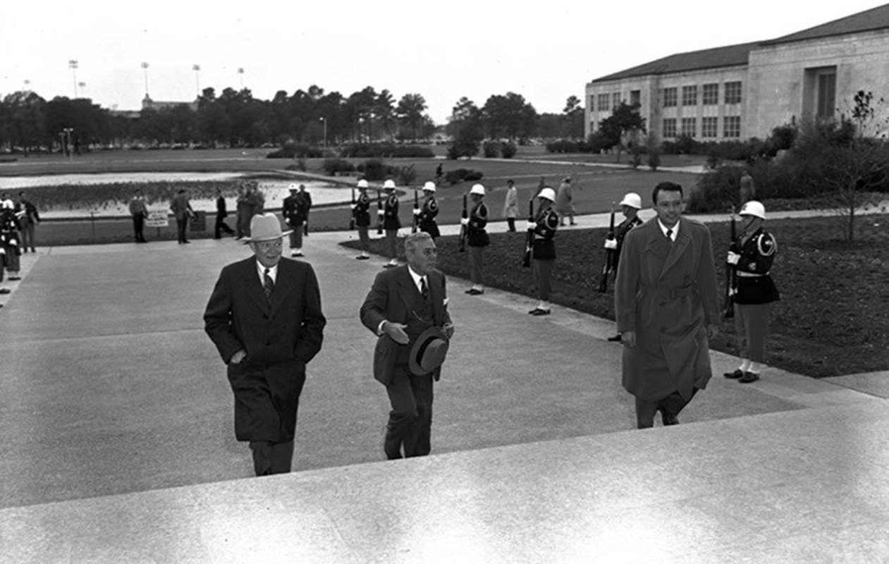 President Eisenhower walking up the steps of E Cullen with the Cullen Rifles behind him