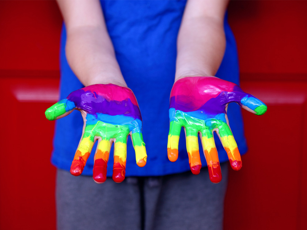 Person with hands painted in a rainbow color