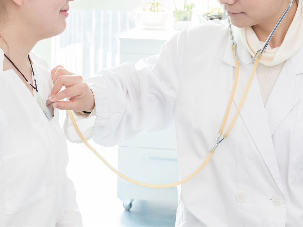 Nurse using stethoscope on a patient