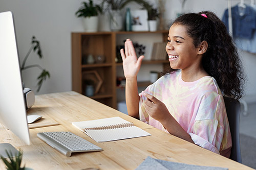 Girl waving at a computer