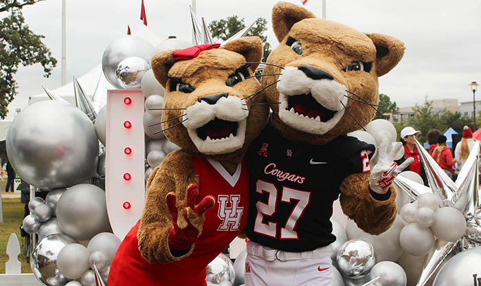 UH Mascots in front of a UH sign
