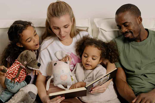 A woman and a man reading to two children