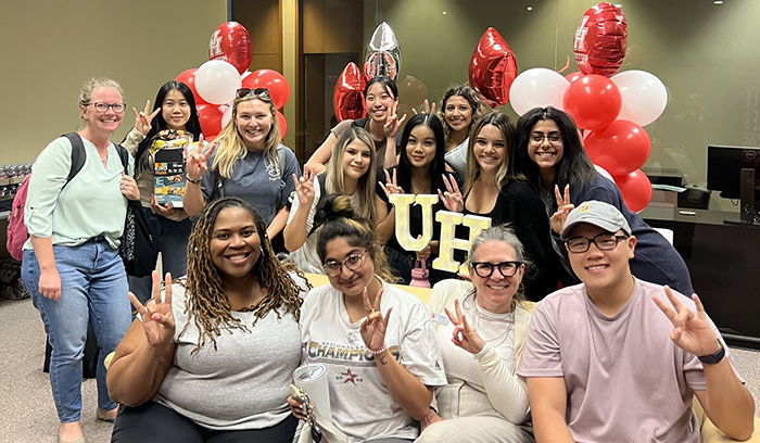 Group of several students flashing the coog sign with a balloon in the background