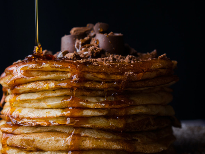 Stack of pancakes with syrup pouring on top of them