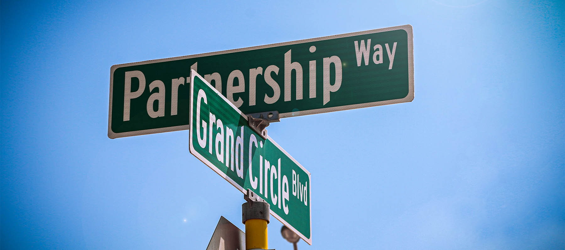 Close up of green metalic street signs that read Partnership Way and GrandCircle Blvd.