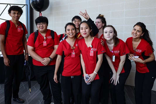 Nursing students wearing red scrubs standing together in a lobby
