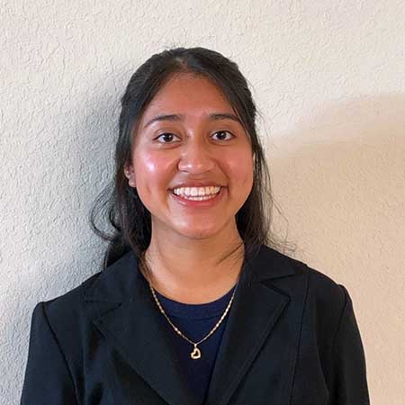 Portrait of a Hispanic woman smiling wearing a black jacket.