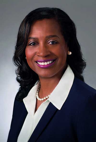 Portrait of a Black woman smiling wearing a business jacket.