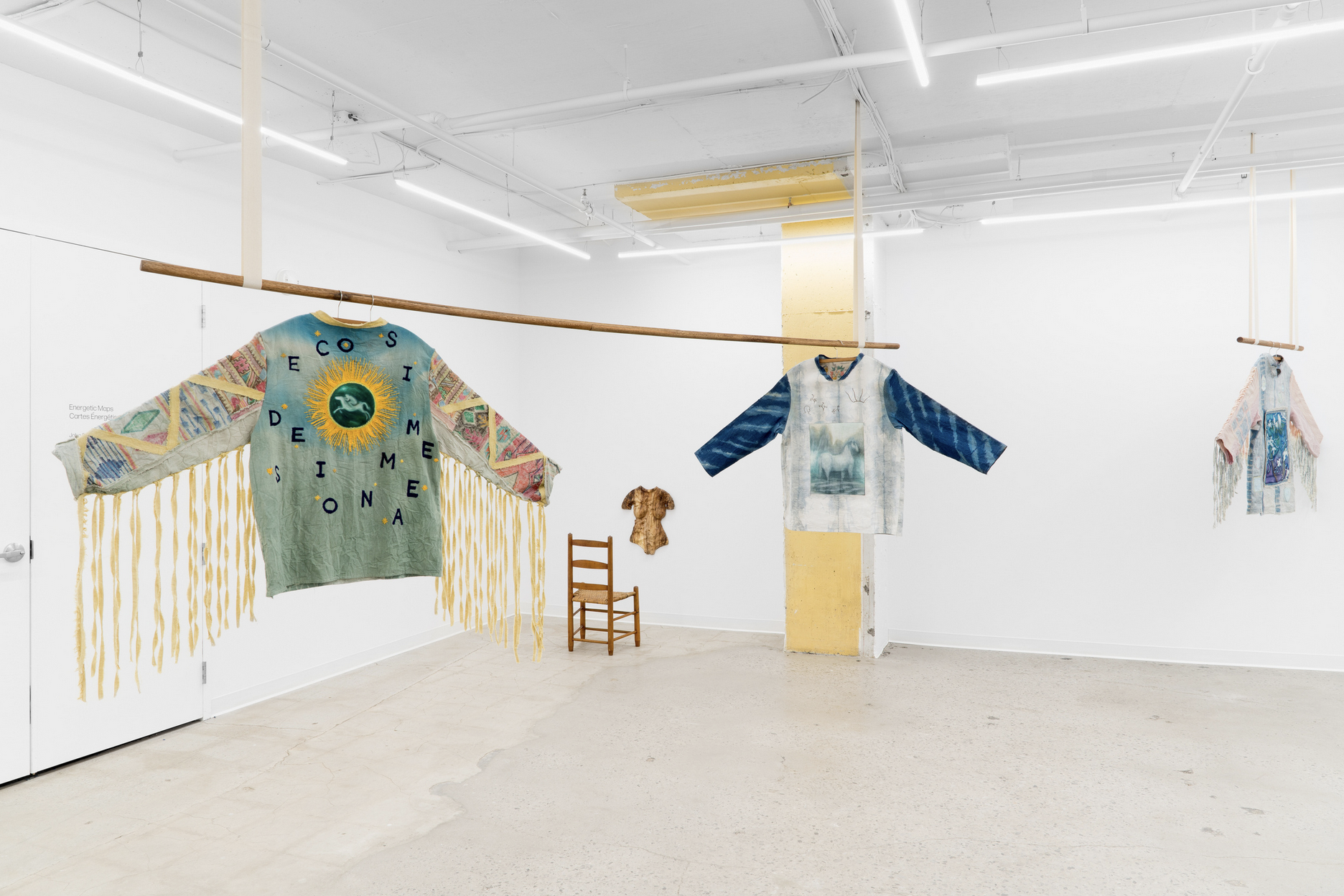 Textile works of fashion jackets hang in an art exhibition space 