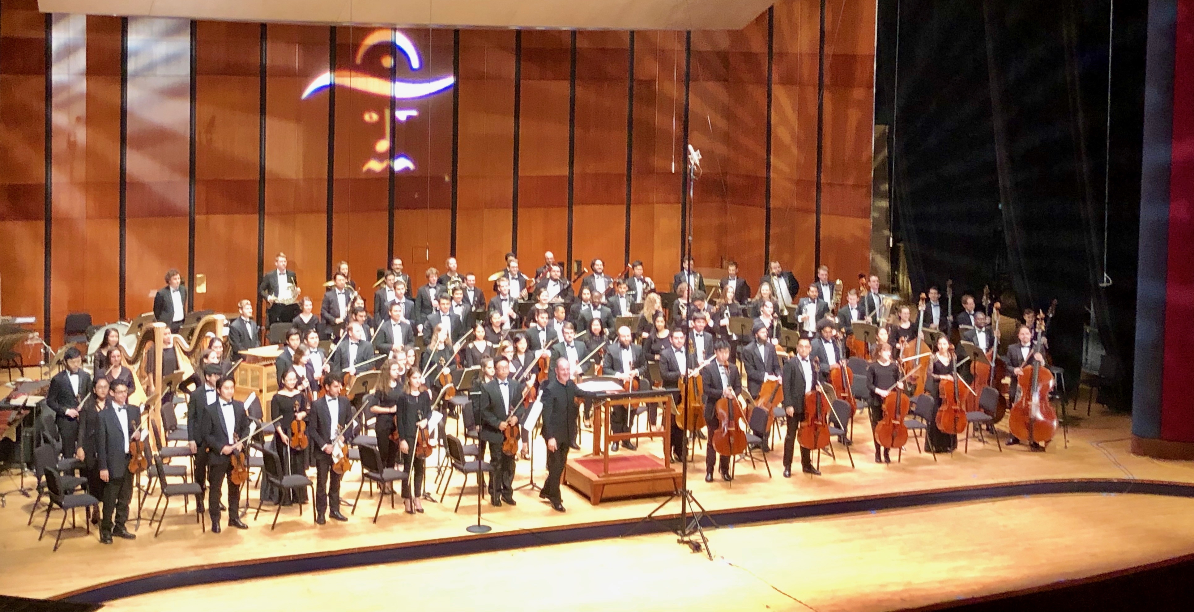 Texas Music Festival full orchestra on stage of the Moores Opera House, taking a bow