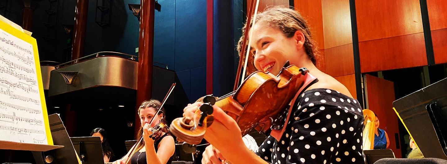 a violinist smiling during a tmf rehearsal
