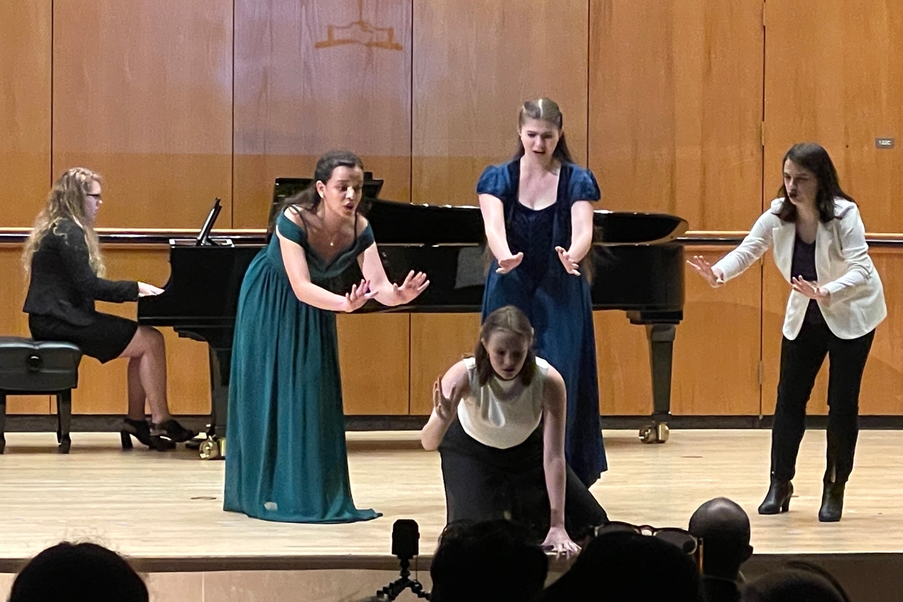 Three singers enacting an operatic scene; gathered around a fourth singer, looking concerned