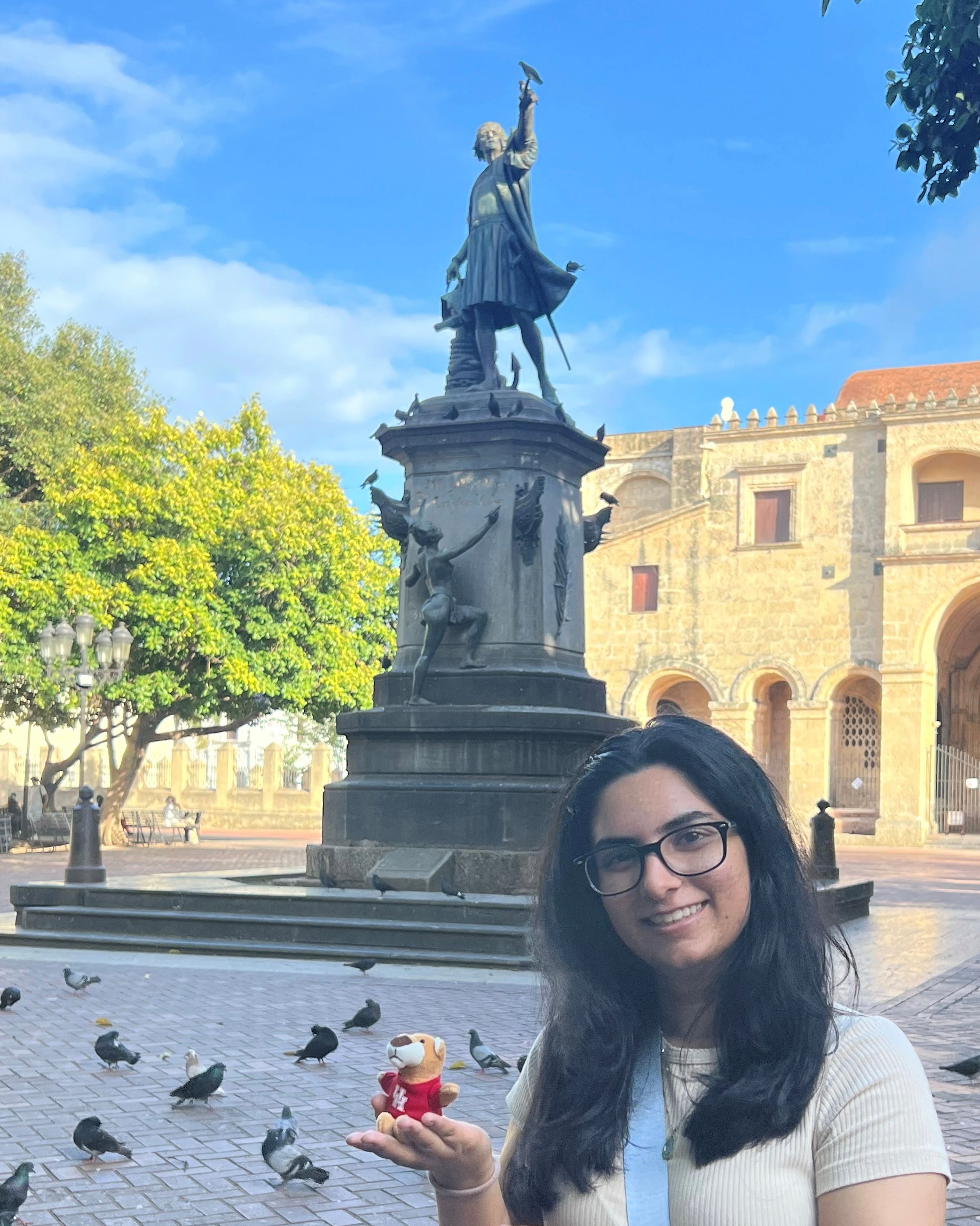 Arushi standing in front of a statue, holding a small cougar plush toy in her hand.