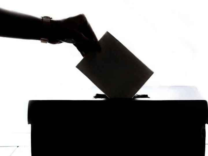 Photo showing person’s hand dropping ballot into voting box
