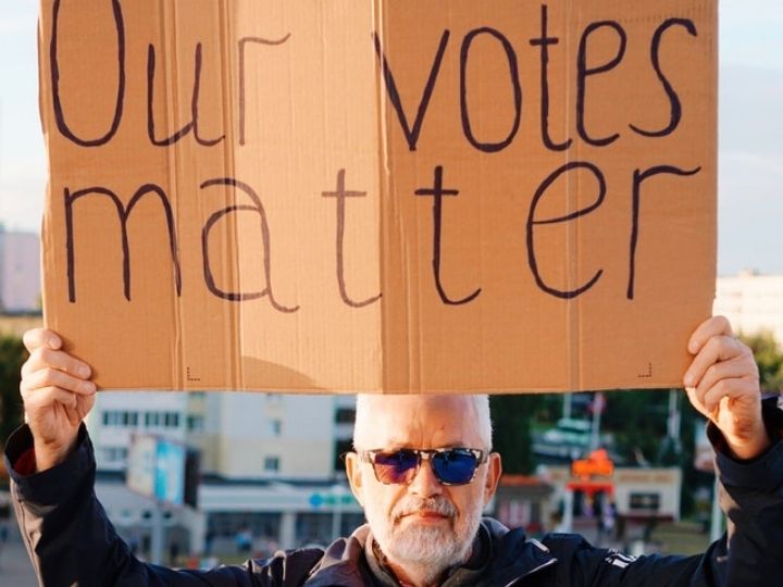 Picture of man holding sign that says all votes matter