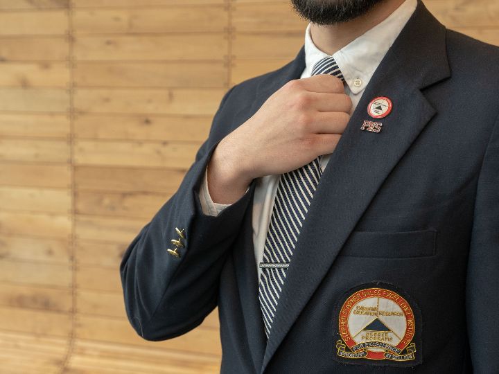 Guy is suit holding label with PES pin on it