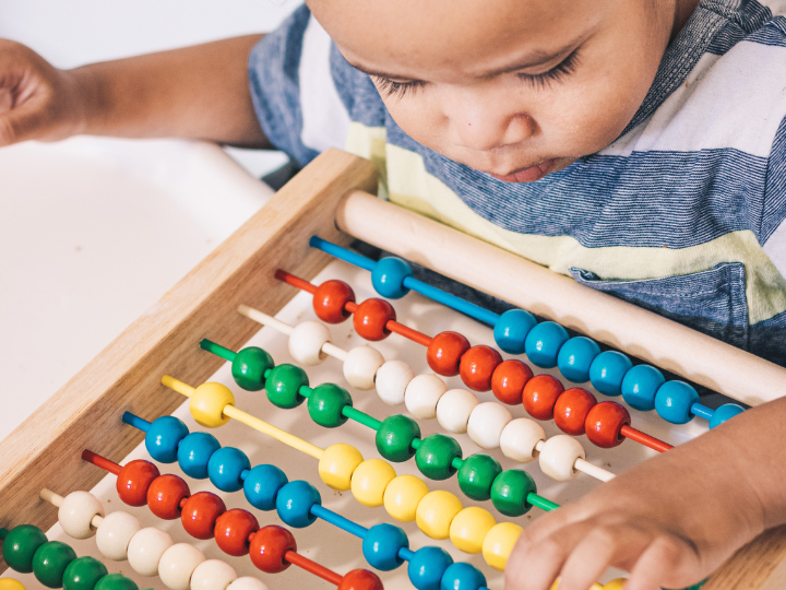 child moving beads on abacus