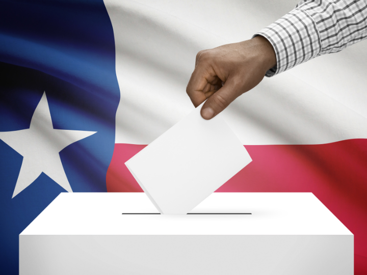 Hand dropping paper vote into ballot box with Texax flag as background.
