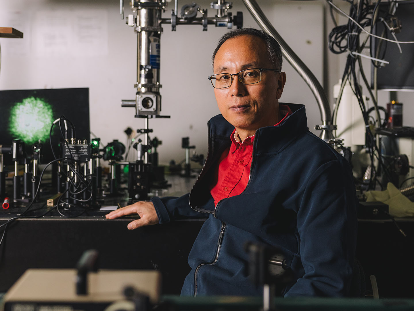 Jiming Bao poses for a portrait with optical lasers inside a Cullen College of Engineering Lab.
