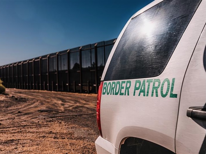 getty image of a border patrol vehicle with the border wall behind it