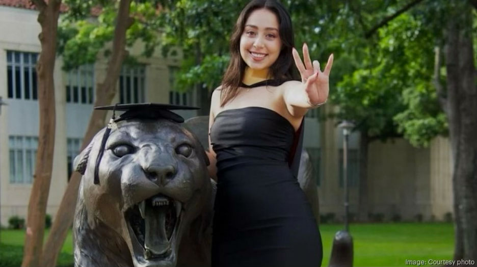 NSM graduate poses for a photo beside the cougar statue behind the Ezekiel W. Cullen Building.