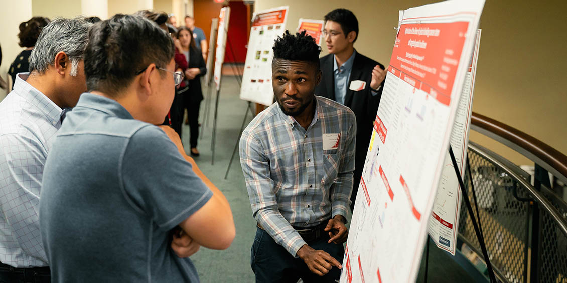 student discussing poster with attendees