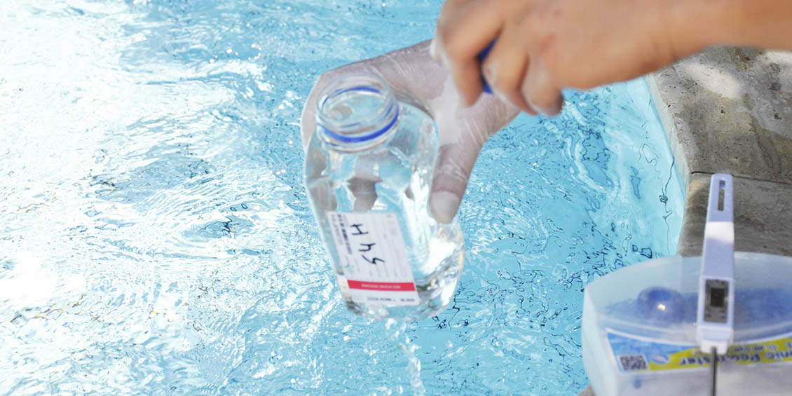 person taking water sample from swimming pool