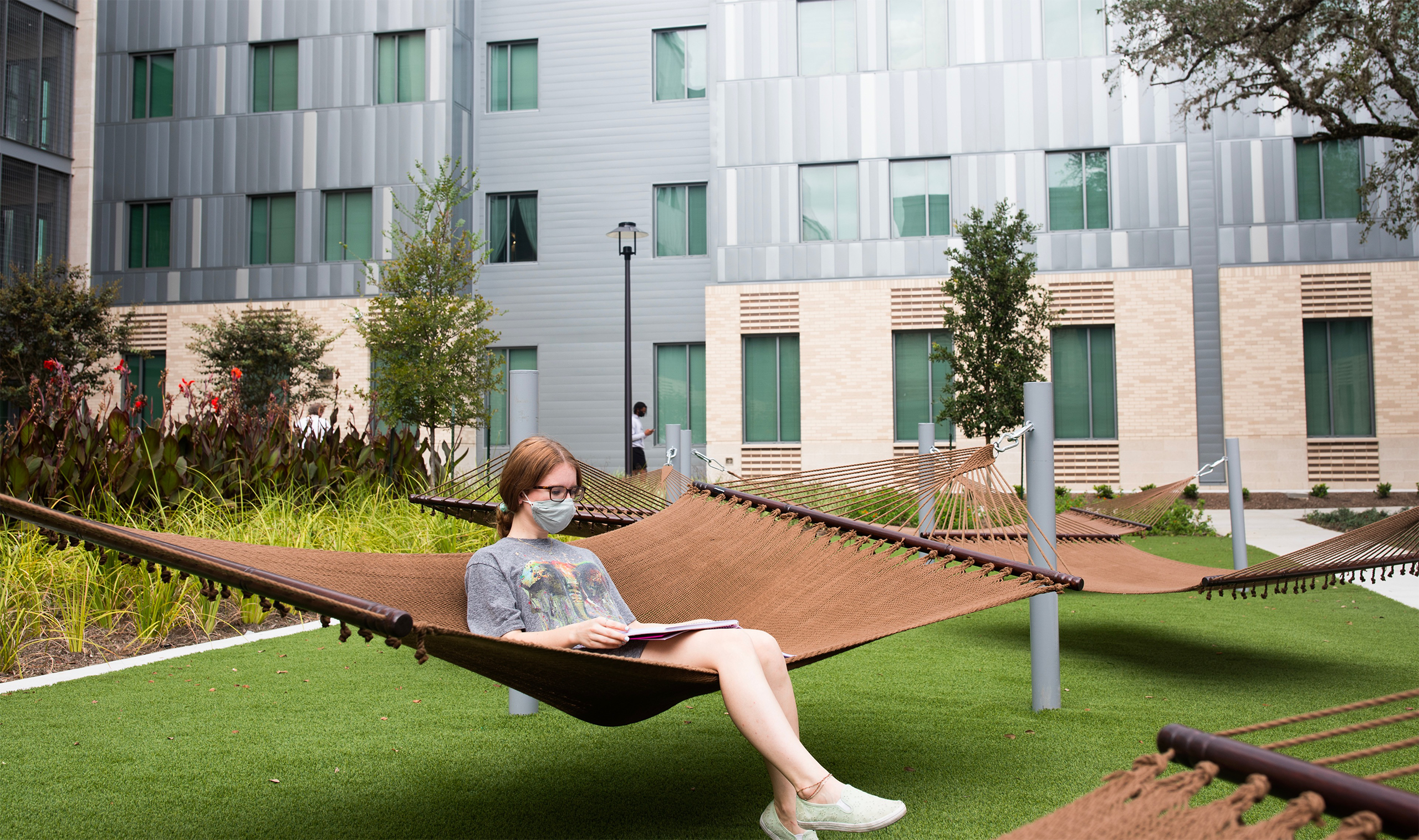 Student sitting on hammock in quad, residential housing