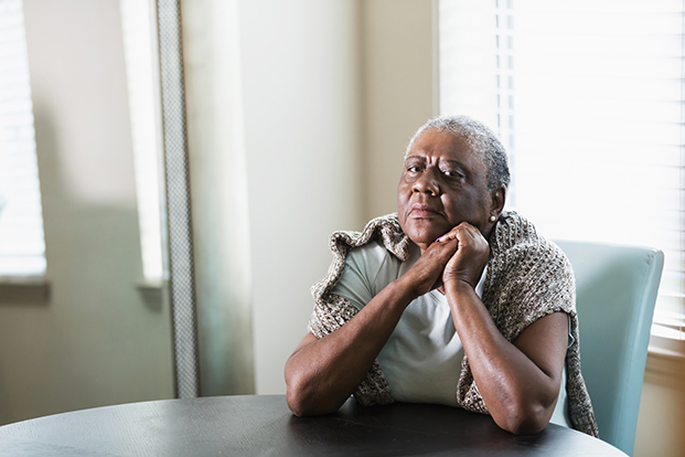 Elderly African American/Black woman sitting at a table alone.