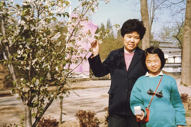 An Asian adult and child stand outside.