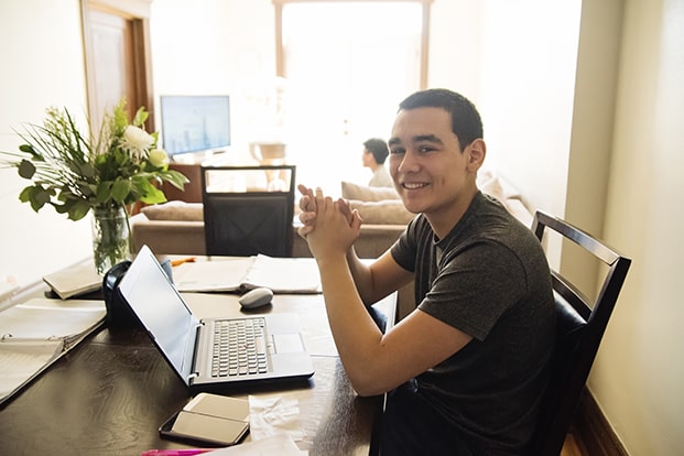 Young male Hispanic teenager sitting at a computer.