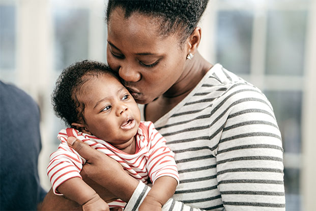 Black mother kissing infant