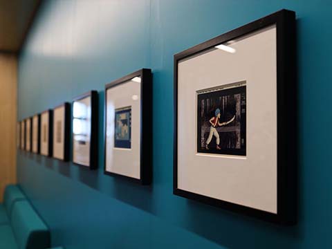 A collection of framed digital ink prints on a blue wall