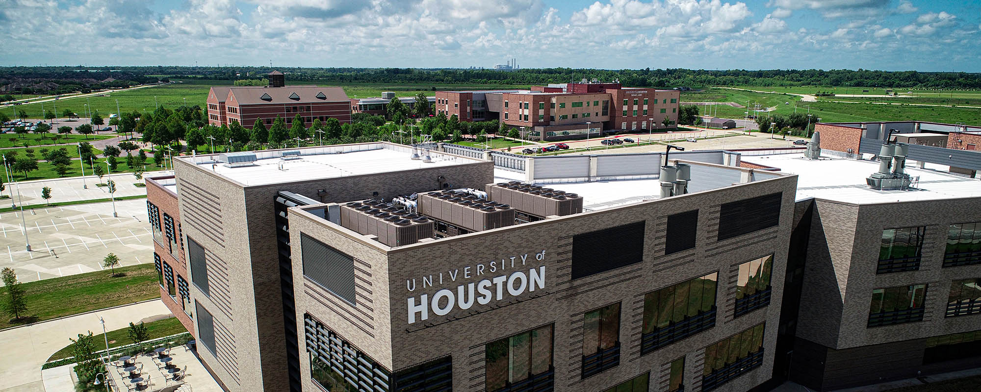 Aerial view of the campus buildings. The University of Houston logo can be seen on the top corner of the foremost building.