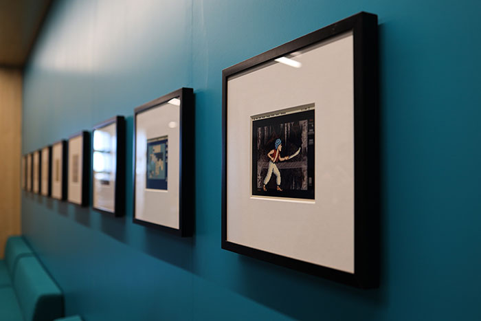 A collection of framed digital ink prints on a blue wall