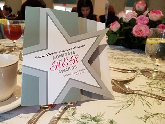 Cover of event program on banquet table surrounded by silverware and dinnerware