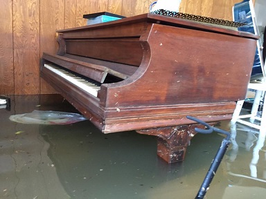 A damaged piano in a flooded room