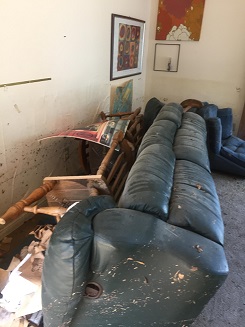 Ripped and broken furniture turned over in flood damaged room