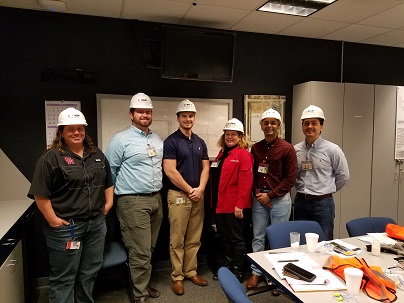 A group of people wearing hardhats standing together in an office